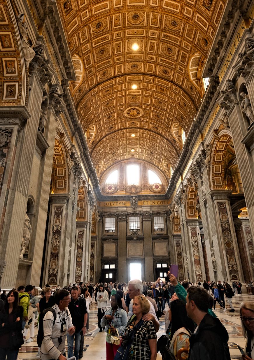 Ornate high ceiling adorned with gold leaf and paintings with crowds of people below