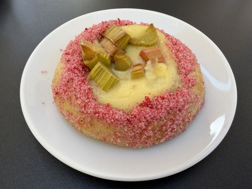 Custard-filled bun topped with chopped rhubarb and pink sugar