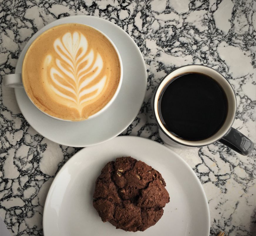 Top down view of latte, cup of coffee, and chocolate cookie on a marble table, Parallel, Minneapolis