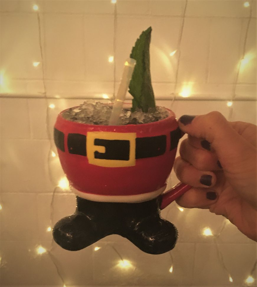 Holiday cocktail, Lawless Distilling Company Hand holding a cocktail in a mug shaped like Santa from the waist down