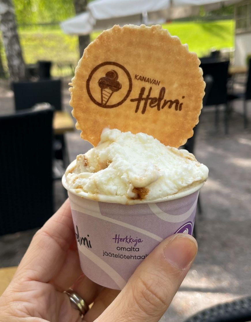 Hand holding cup of ice cream topped with a wafer cookie