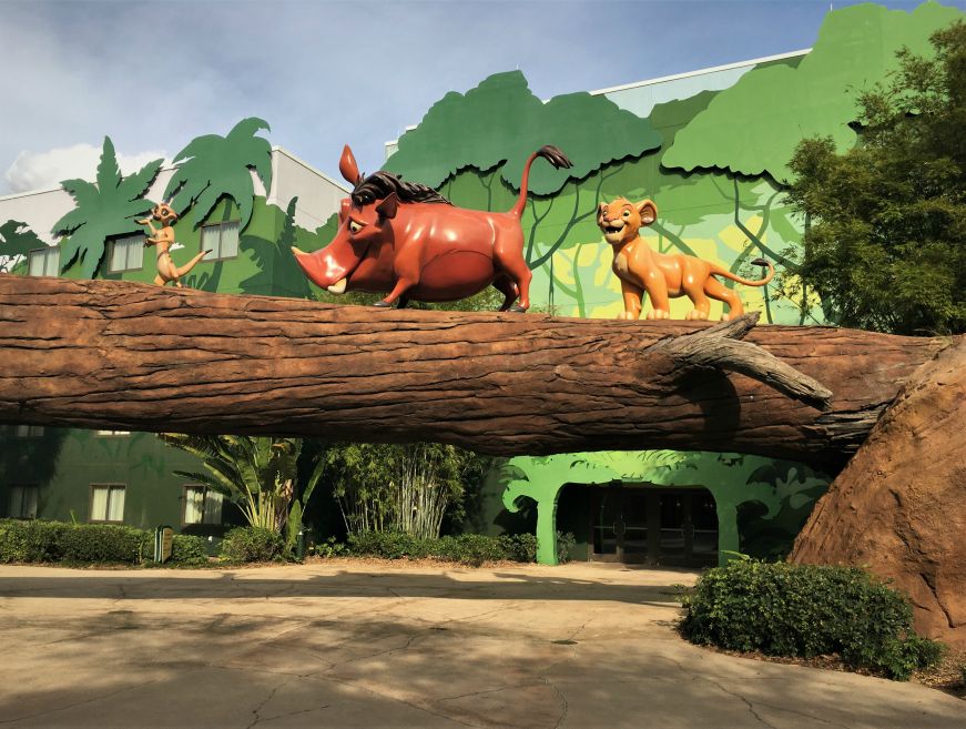Statues of Simba, Timon, and Pumba with hotel building in background, Art of Animation Resort
