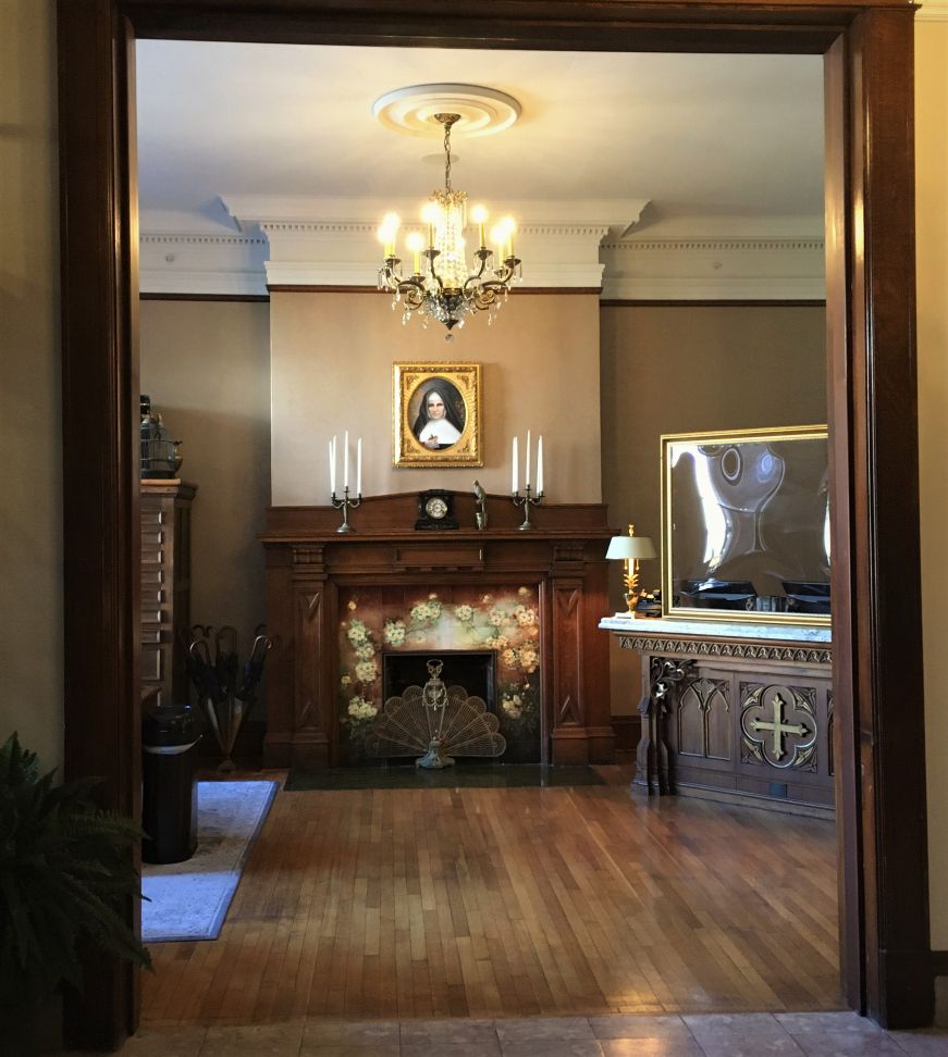 Ornate lobby with fireplace, crystal chandelier, and a painting of nun