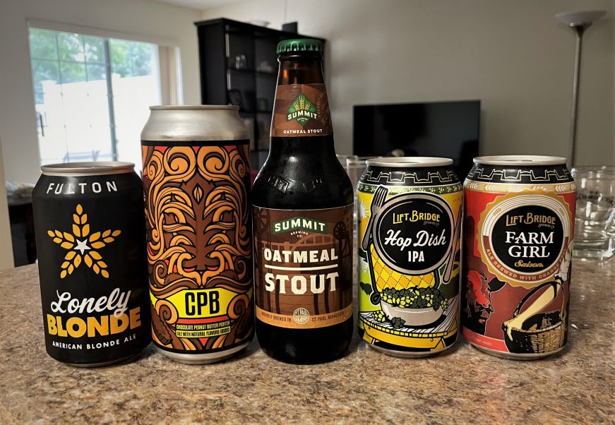 Four cans and a bottle of craft beer arranged on a kitchen counter