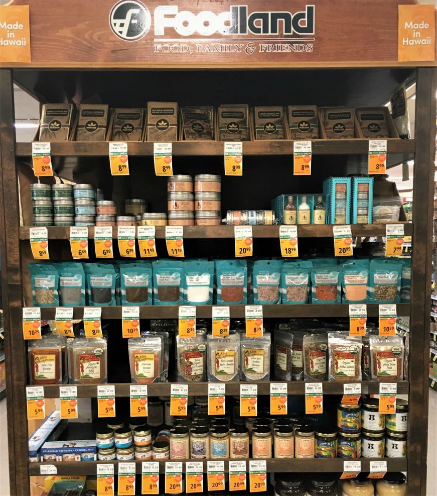 Wooden shelves of seasonings with signs reading "Made in Hawaii" at a grocery store