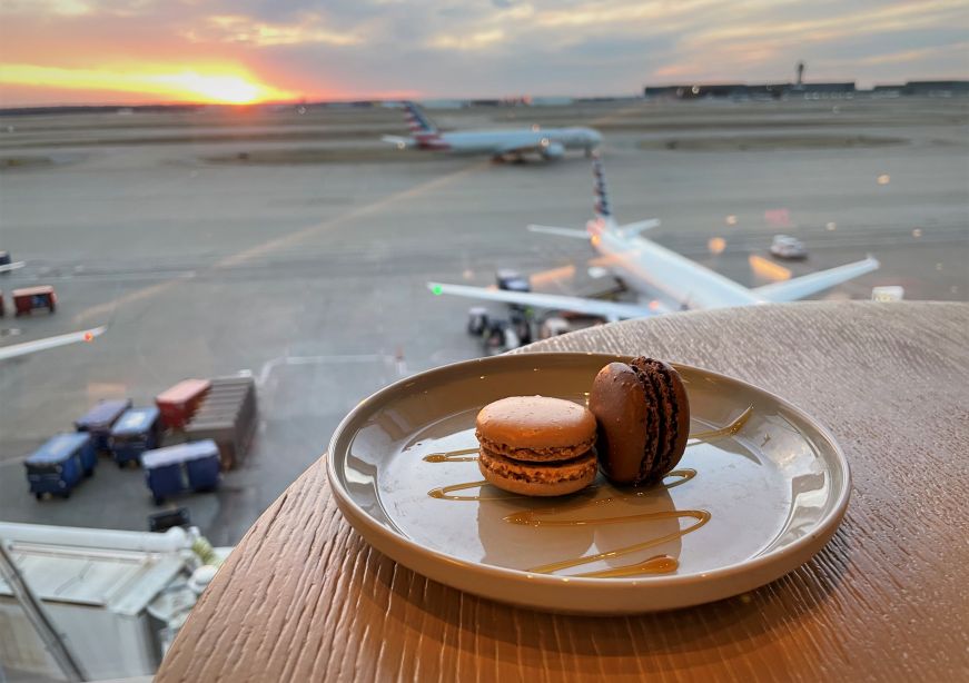 Plate of two macarons in front of a window overlooking an airport runway