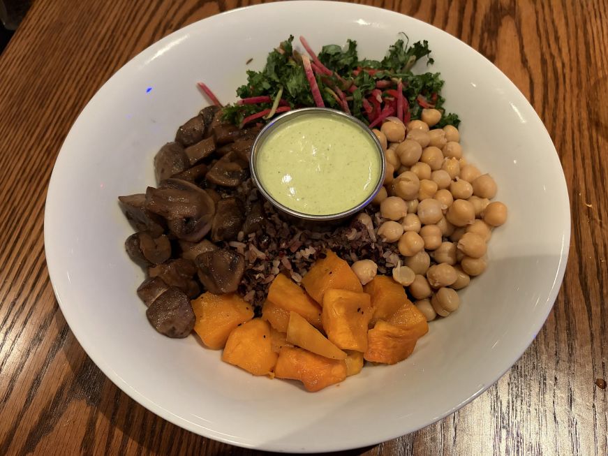 Bowl of rice topped with mushrooms, squash, chickpeas and kale with a cup of Green Goddess dressing in the center