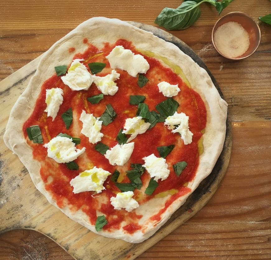 Uncooked margherita pizza on table with basil leaves and cup of salt on the side, 1889 Pizza Napoletana, Kansas City, Kansas