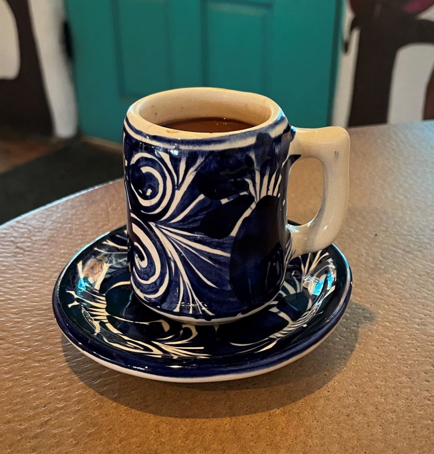 Small blue ceramic cup holding a chocolate beverage