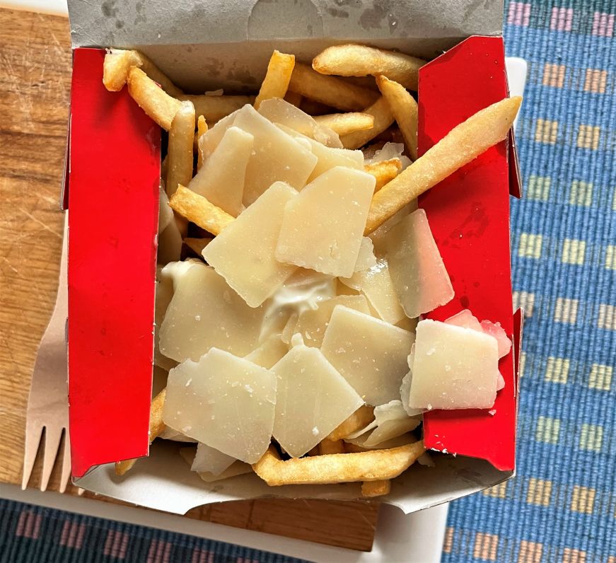 Box of fries topped with mayo and shaved Parmesan