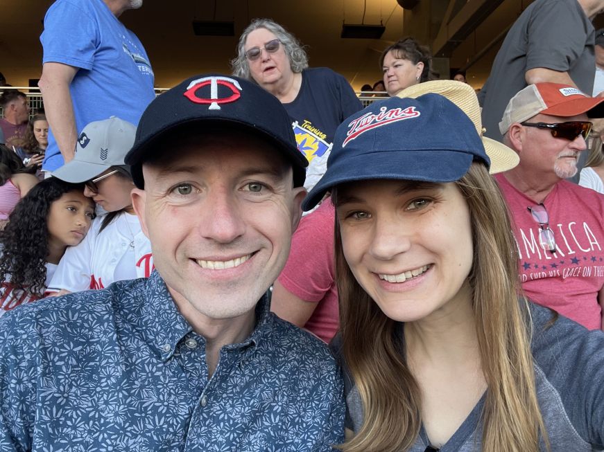 Mike and Stacy at Target Field Stacy and Mike sitting at a stadium wearing Twins baseball caps
