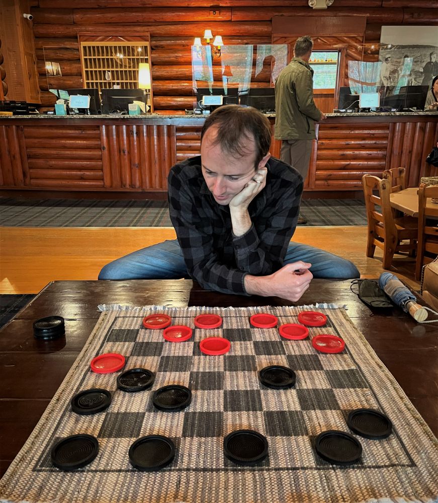 Mike playing checkers on a coffee table in a hotel lobby with rustic decor
