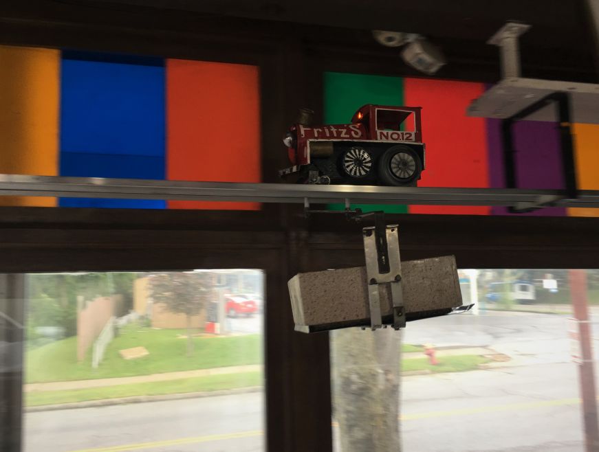 Model train running on a track suspended from the ceiling and carrying a metal box below, Fritz's Railroad Restaurant, Kansas City, Kansas