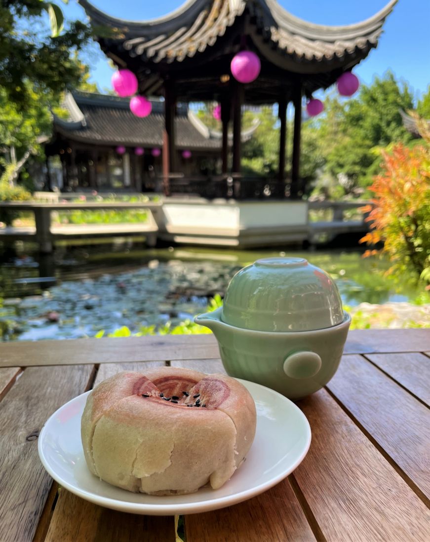 Mooncake and cup of tea with a pond and pagoda in the background