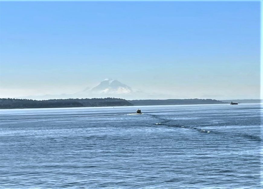 Snow covered mountain in the distance with water and boats in the foreground