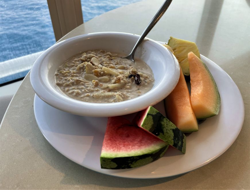 Bowl of muesli and sliced melon with ocean in the background