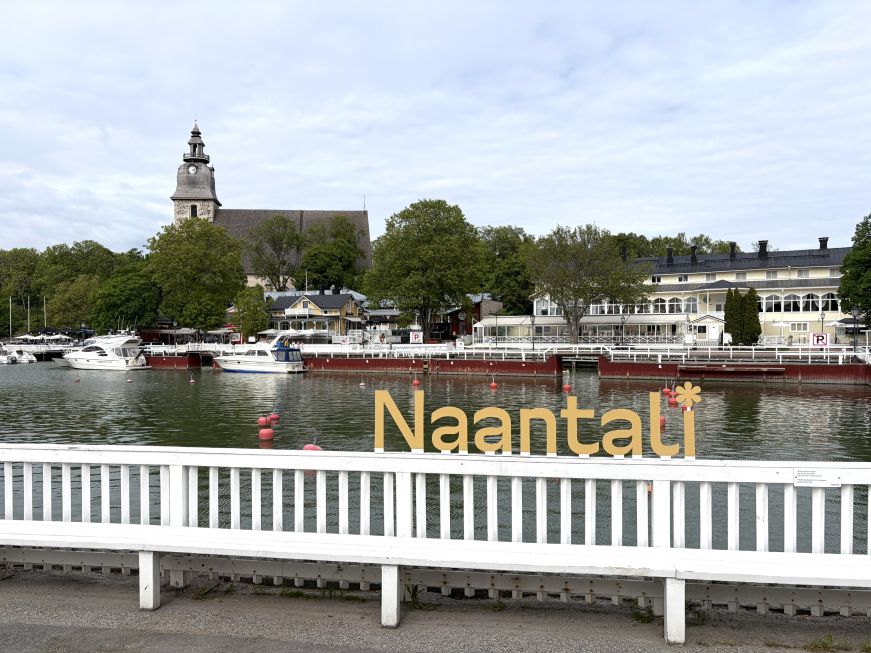 Small harbor with a sign reading "Naantali" and a church on a hill in the background