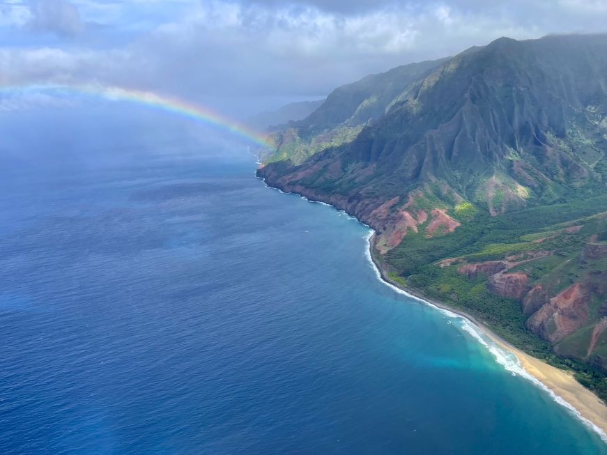 Aerial view of a rugged coastline with a rainbow