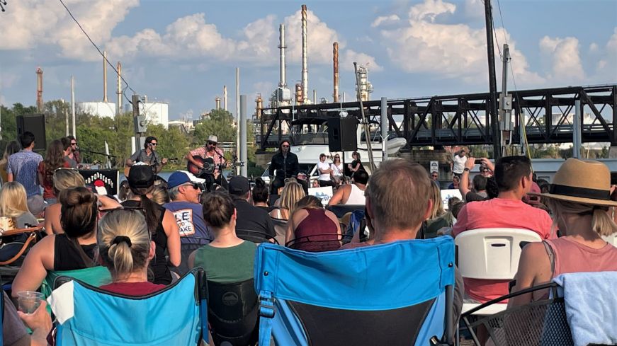 Crowd of people sitting in lawn chairs watching NEEDTOBREATHE on a small stage