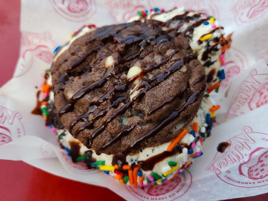 Nellie's Ice Cream Ice cream sandwich made with chocolate cookies and rolled in rainbow sprinkles