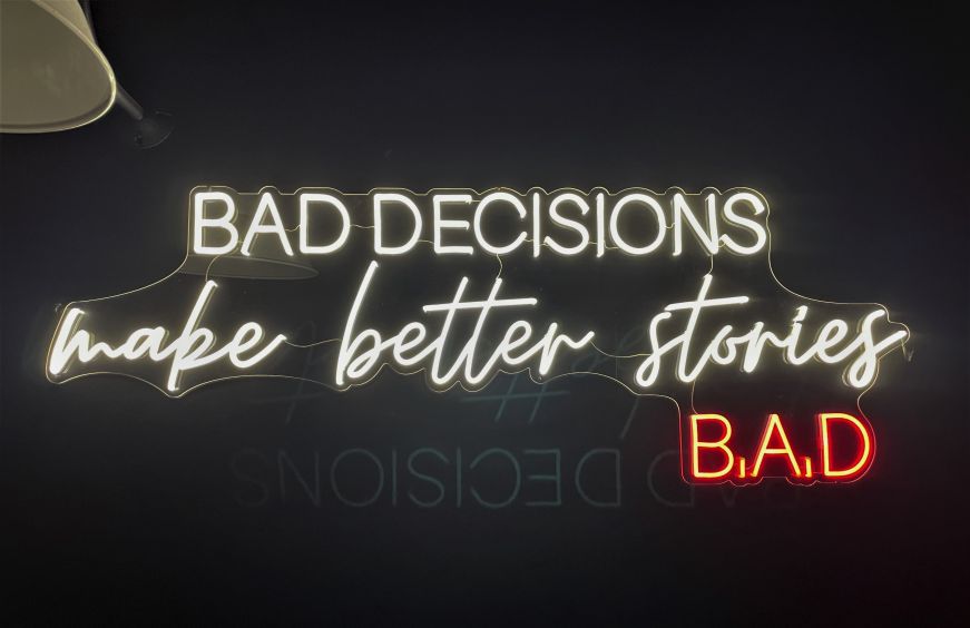 Neon sign at Billy After Dark Neon sign reading "Bad decisions make better stories"