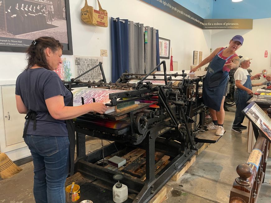 People operating antique printing presses