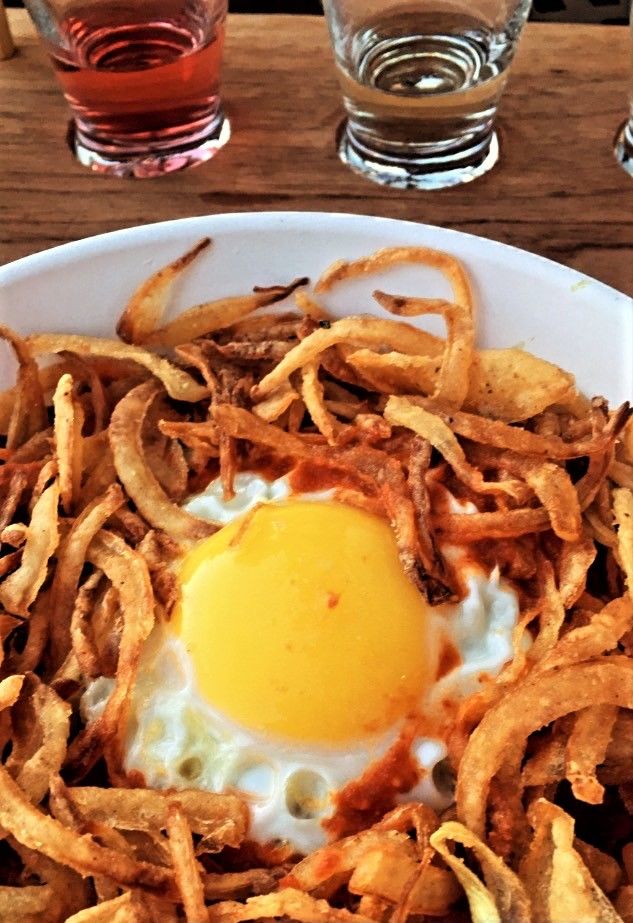 Bowl of rice, beans, and spinach topped with fried onions and sunny side up egg