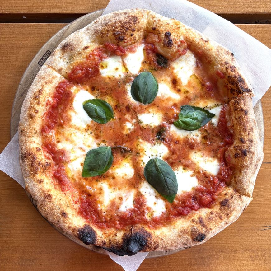 Neapolitan-style pizza with mozzarella cheese, tomato sauce, and basil