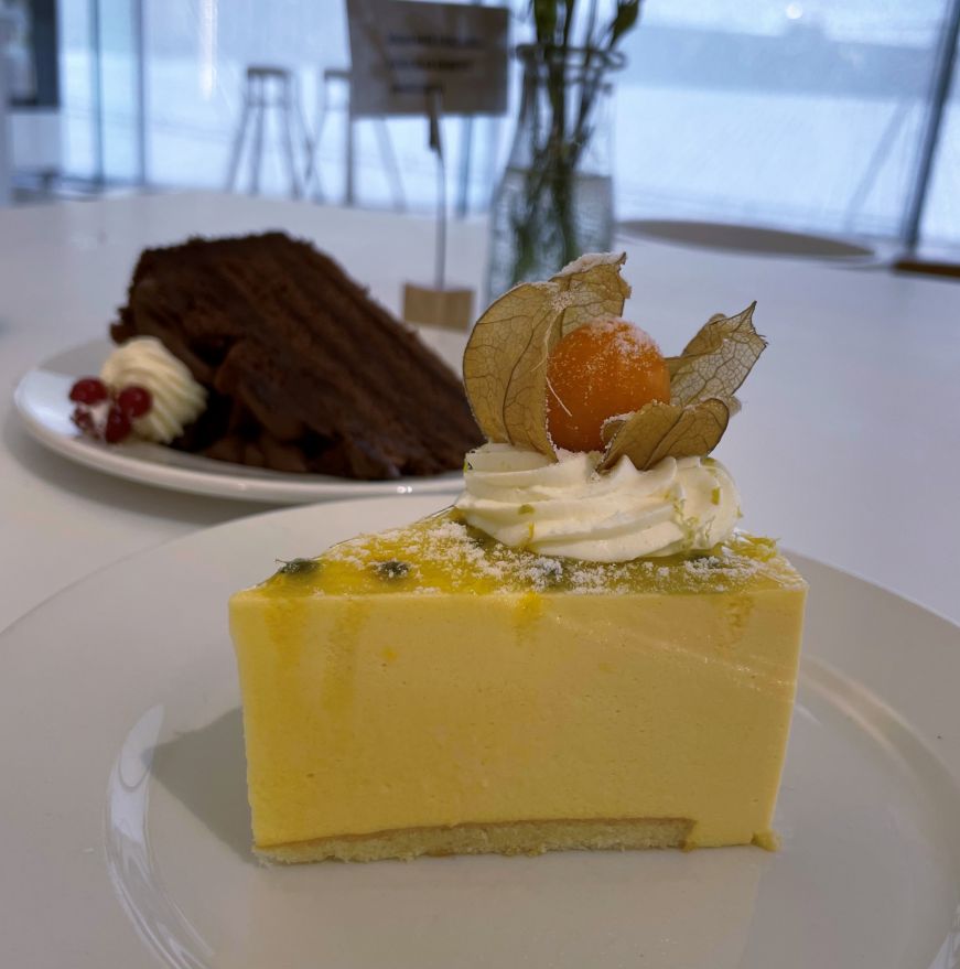 Passionfruit cake, Oodi Cafe Slice of light yellow cake garnished with a small piece of fruit