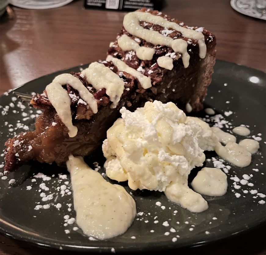 Pecan pie, O'Shaughnessy Distilling Co. Piece of pecan pie on a plate with a dollop of whipped cream
