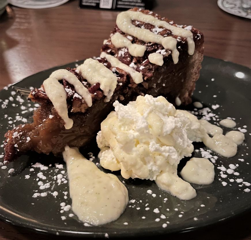 Piece of pecan pie on a plate with a dollop of whipped cream