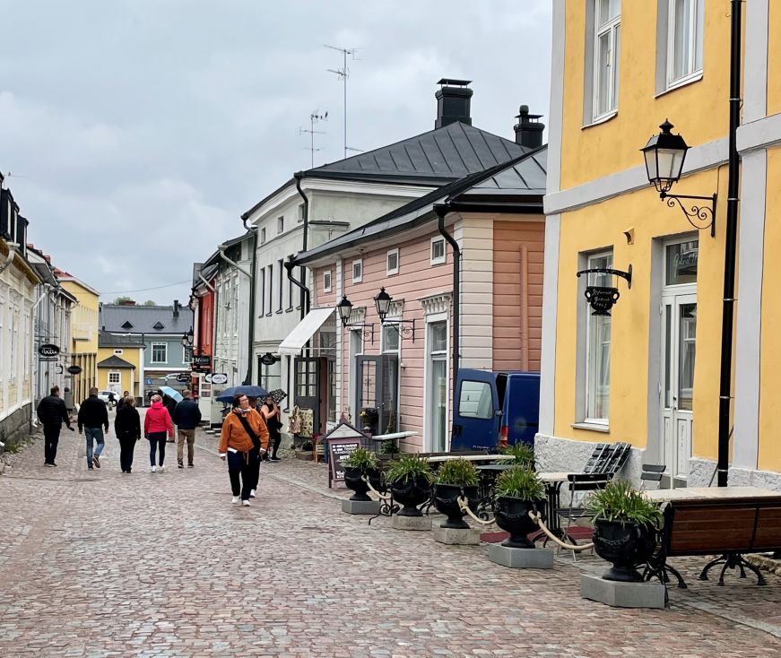 Cobblestone street with pedestrians and colorful wooden shops