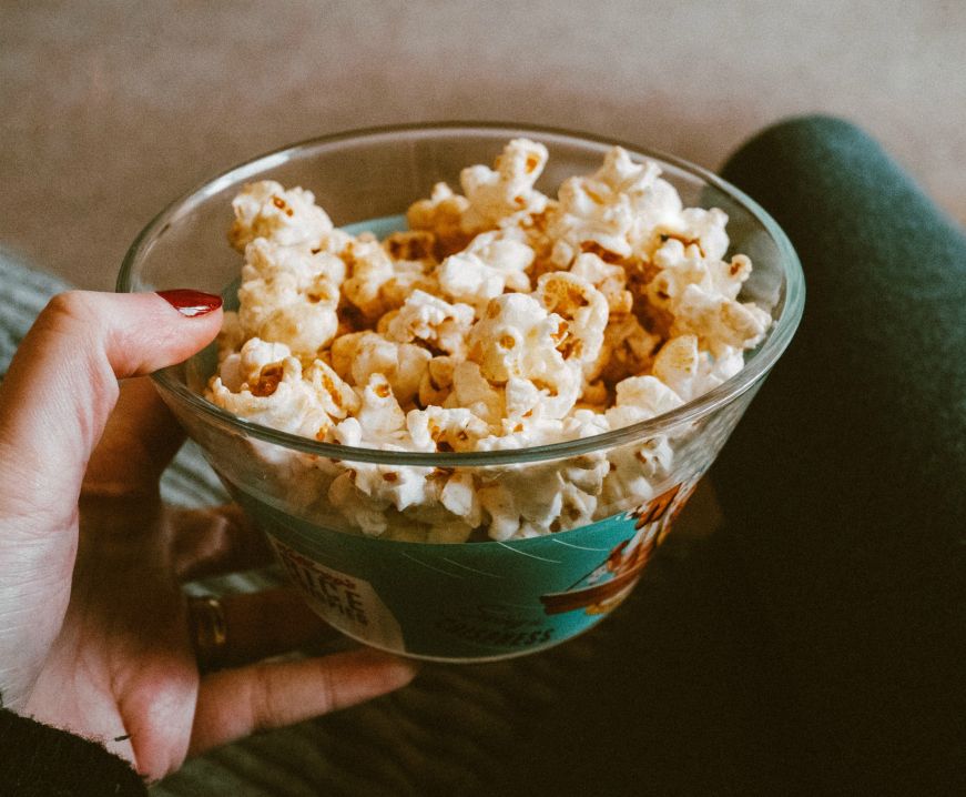 Hand holding glass bowl of popcorn