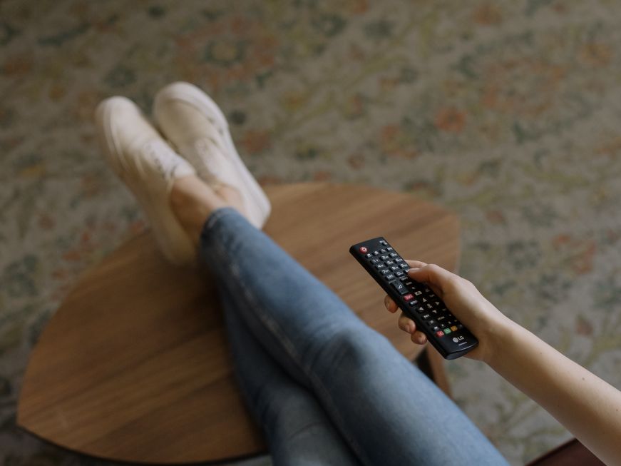 Woman's legs propped up on coffee table and her hand holding a remote