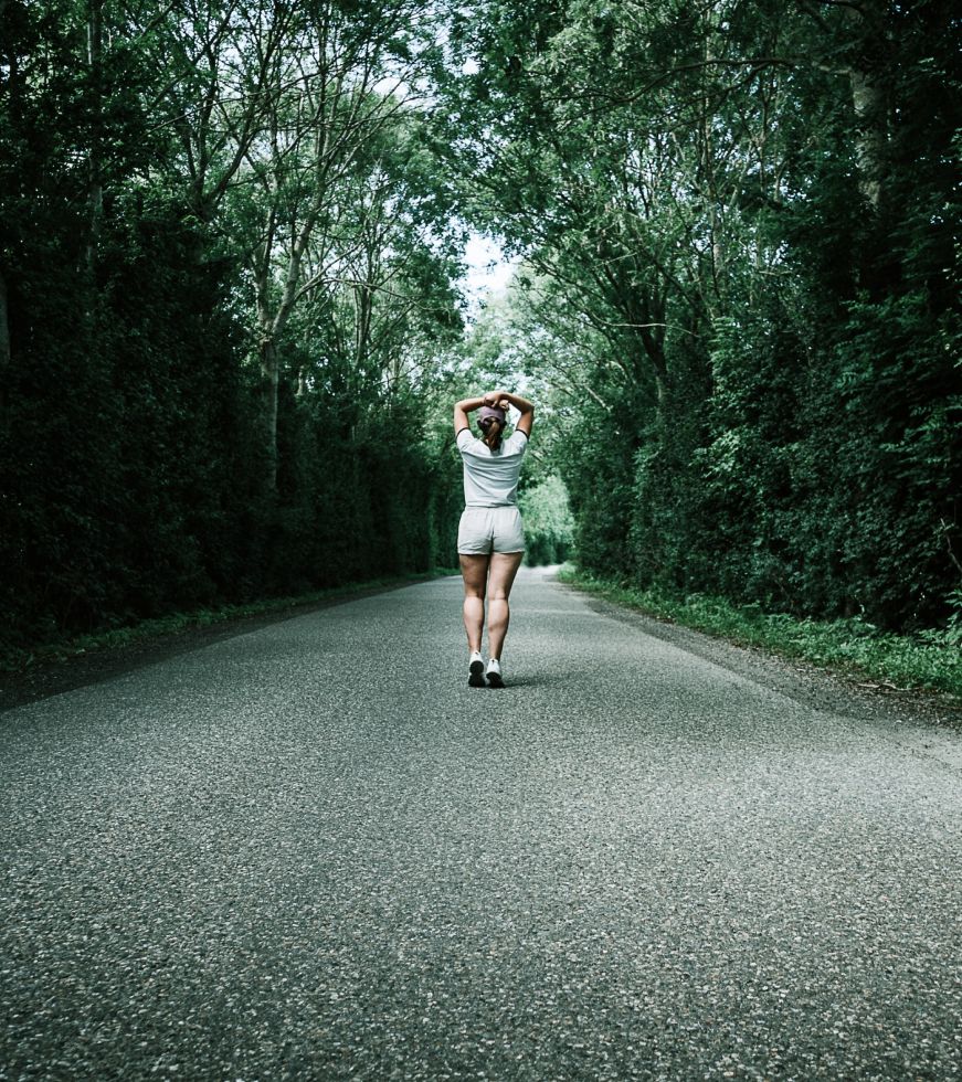 Woman standing on pavement surrounded by woods