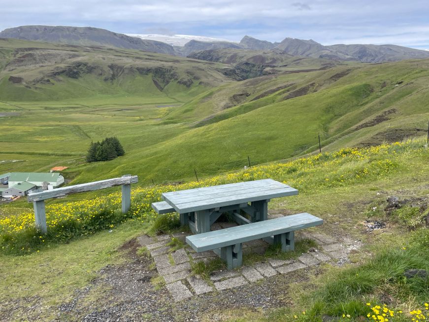 Picnic table on a green hill with scenic mountains in the background