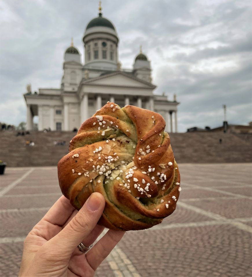 Hand holding pastry in from of an ornate white cathedral