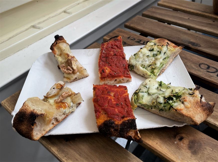 Pizza from Casa Manco, Mercato Trestaccio Plate with six rectangular slices of pizza with a variety of toppings