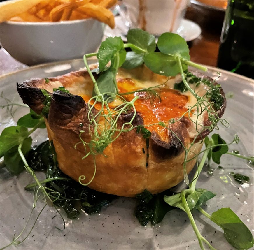 Individually-sized savory pie filled with vegetables and cheese and topped with fresh herbs