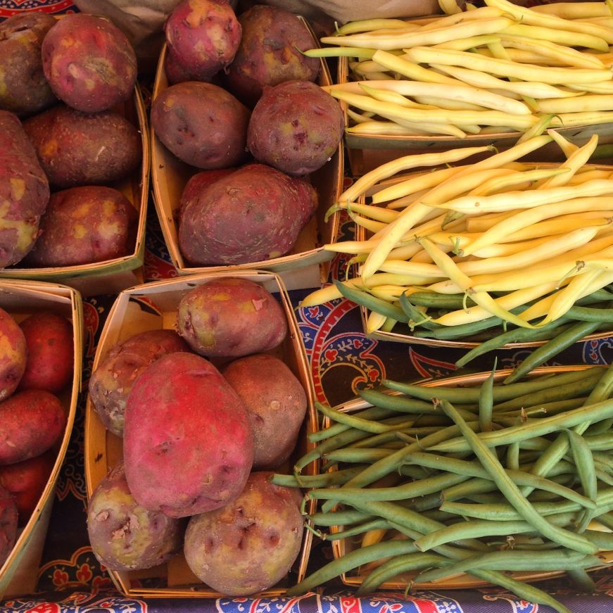 Baskets of potatoes and green and yellow beans at farmstand