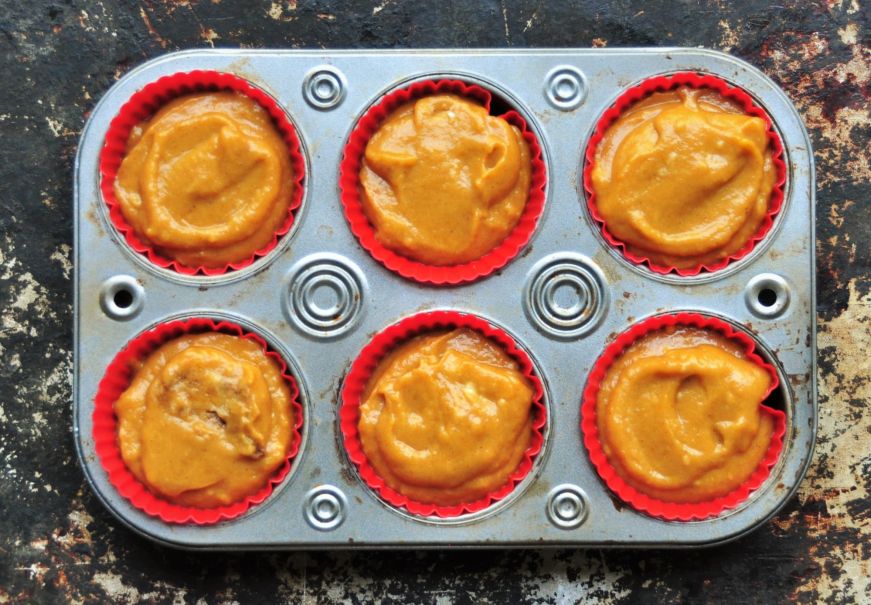 Muffin tin filled with batter for pumpkin muffins