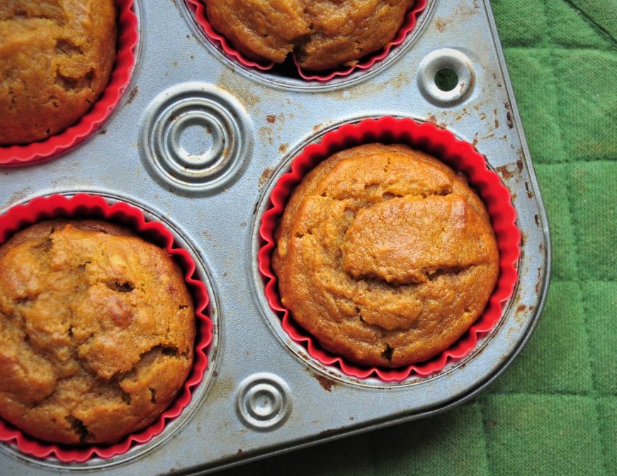 Pumpkin muffins in a tin with a green potholder