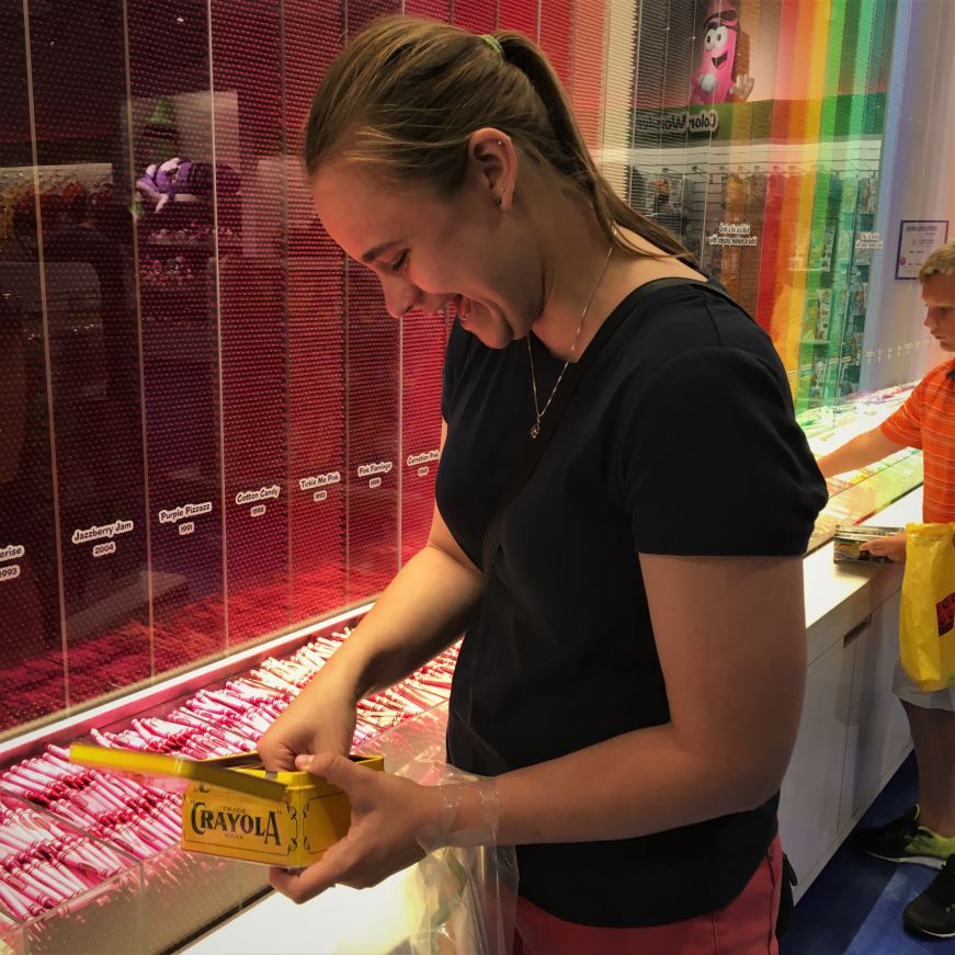 Rachel picking out crayons from a large colorful display at the Crayola Store, Mall of America