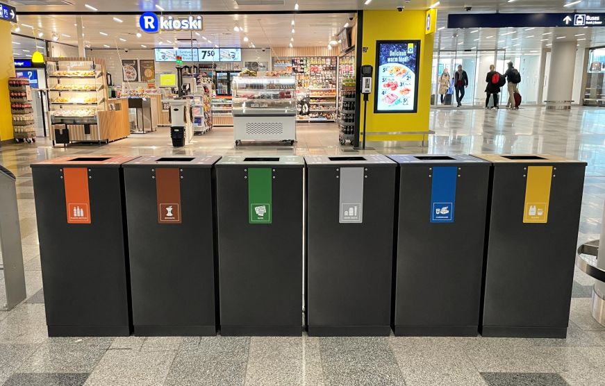 Row of several color coded trash, recycling, and compost bins