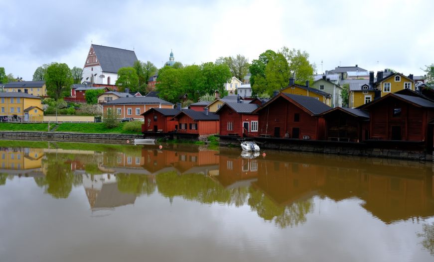 Red wooden warehouses, pastel houses, and cathedral along a river