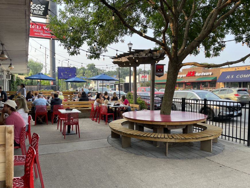 Restaurant patio with a communal table built around a large tree