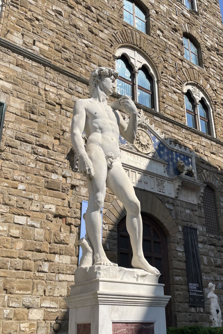 Replica of Michelangelo's David standing in front of a palace