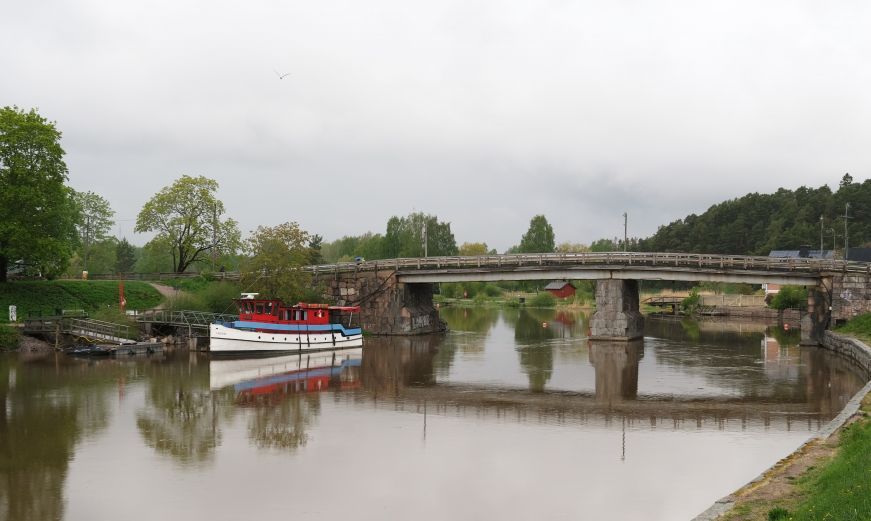 River with a boat moored on the shore and a small bridge