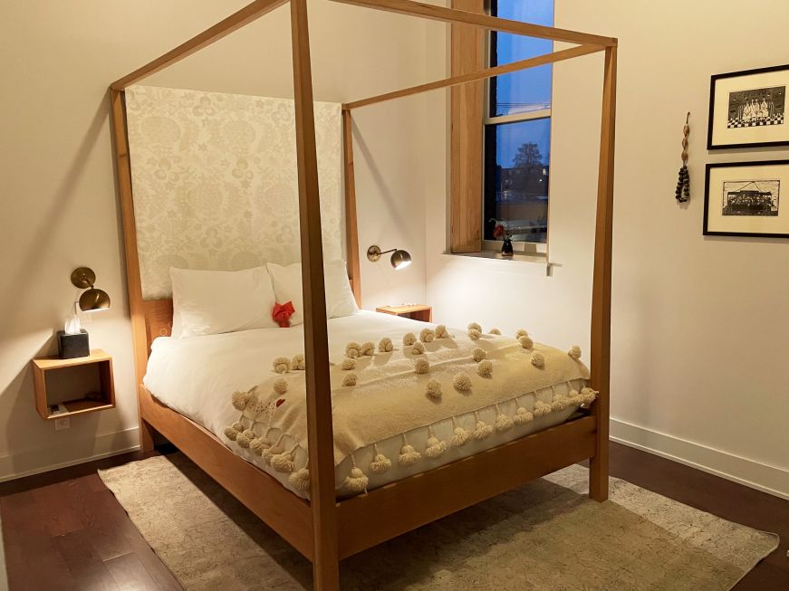 Hotel room with a bed with a white bedspread and a canopy-style bed frame