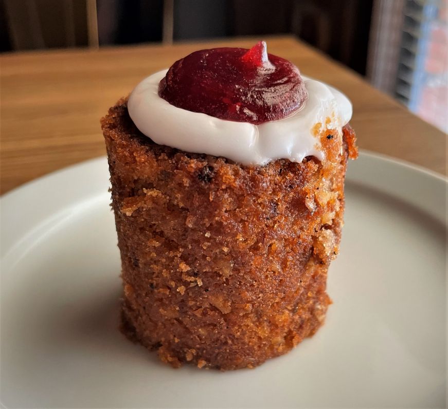 Small cylindrical cake topped with icing and raspberry jam